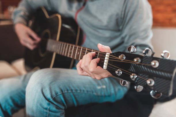 A man playing an acoustic guitar, symbolizing creative hobbies for men like music production to boost confidence and reduce stress.