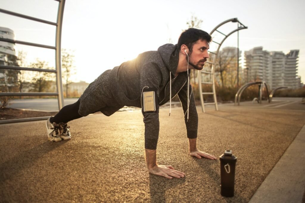 Image of a man performing a push-up outdoors at sunrise with a water bottle nearby, symbolizing off-grid fitness, alongside the title "Off-Grid Fitness: 7 Ruthless Alpha Challenges to Build Strength Without a Gym."