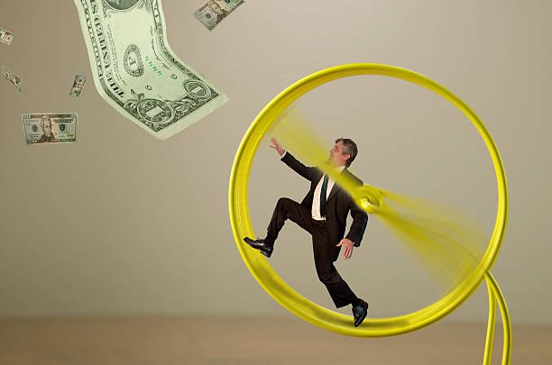 Image of a man in a suit running inside a yellow hamster wheel with dollar bills falling around him, symbolizing financial stoicism, alongside the title "7 Ruthless Financial Stoicism Habits for Emotionless Men Who Reject Consumerism."