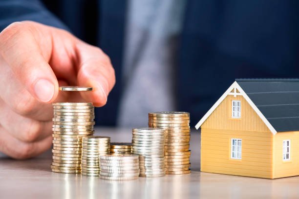 Alt Text: Image of a hand stacking gold coins next to a small model house, symbolizing wealth building, with the title "Wealth Building Men 2025: 7 Quiet Strategies for Financial Freedom Without the Flash" displayed.