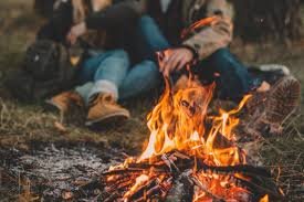 "Campfire close-up during a relaxing micro-adventure with a couple sitting outdoors in boots and jackets"