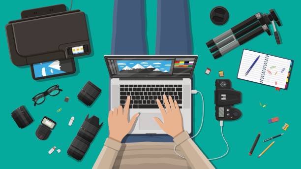 An overhead illustration of a creative professional using one of the best editing laptops for photo or video work, surrounded by their camera, lenses, and a tripod, representing a typical creator's workflow.