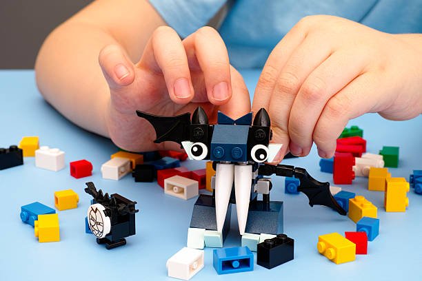 A child's hands building a bat-like monster with colorful toy bricks, an excellent example of screen-free gadgets that keep kids busy and spark creativity.