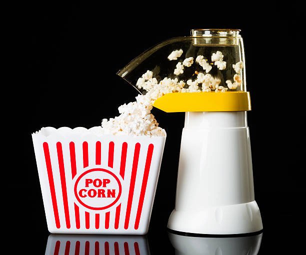 Hot air popcorn maker popping fresh, fluffy popcorn directly into a classic red and white popcorn box. Top 5 popcorn makers on Amazon.