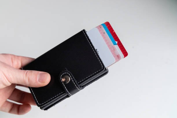 Black minimalist RFID wallet with leather strap and quick-access pop-up feature holding multiple credit cards.