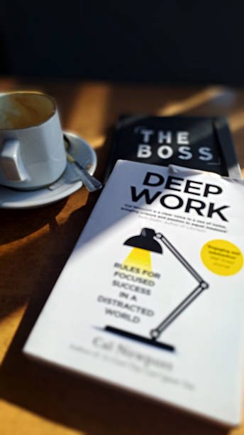 Cal Newport's book Deep Work on a wooden table next to a coffee cup, illustrating focused work and productivity.